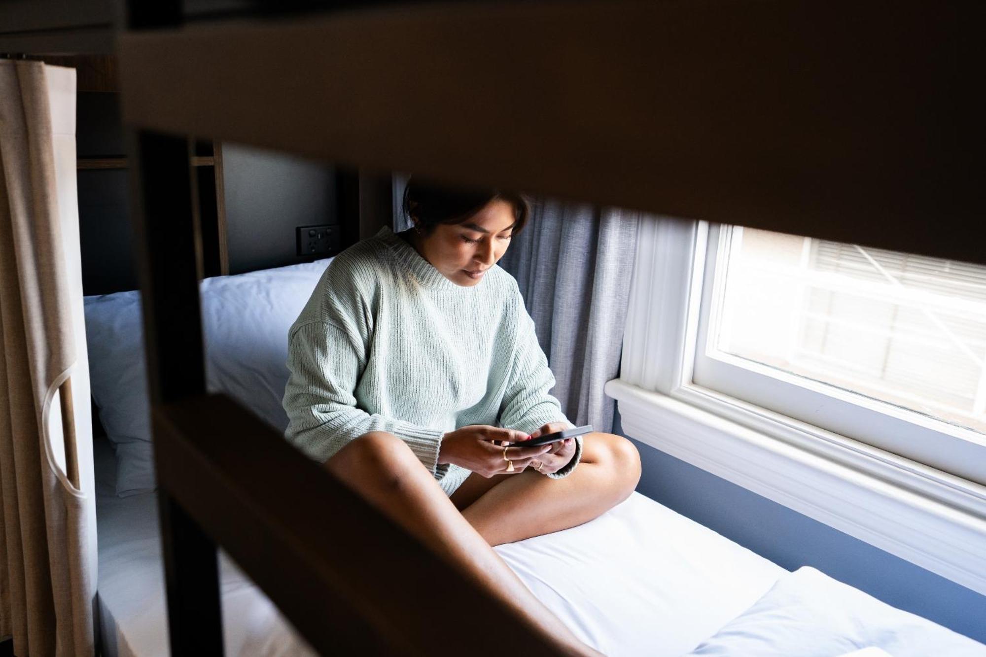 Haka House Christchurch Phòng bức ảnh A woman sitting on a bunk bed